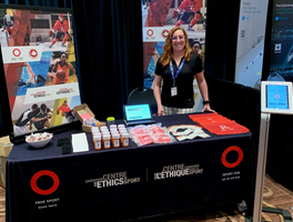 A woman stands behind an outreach booth table