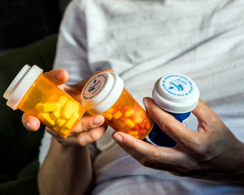 Person holding 3 prescription medication bottles filled with pills